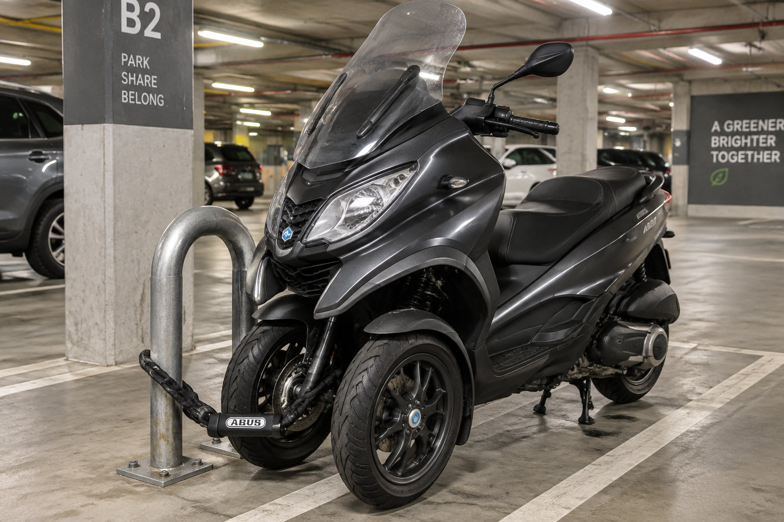 Un scooter à trois roues est attaché avec un antivol dans un parking collectif urbain.